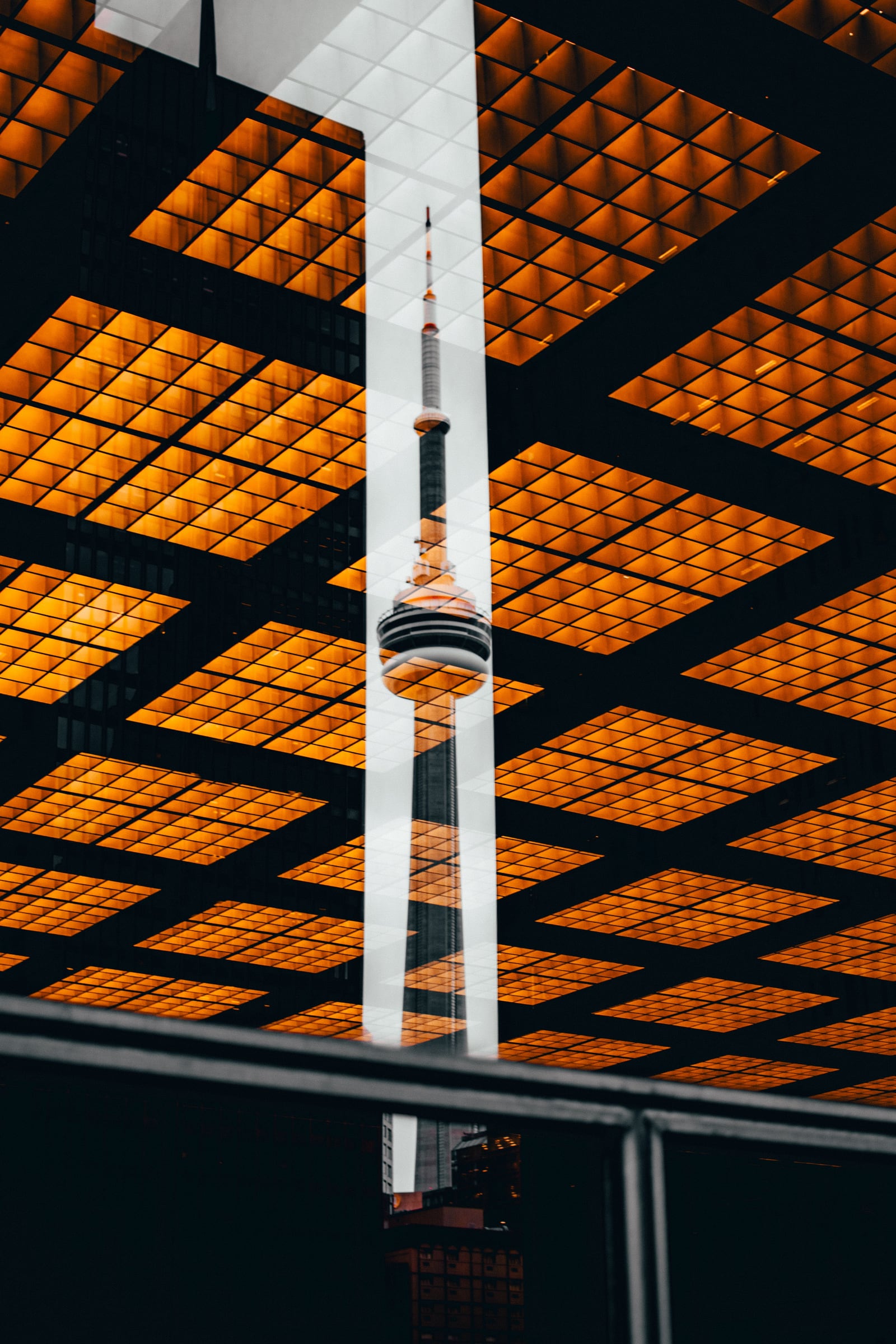 A layered reflection of the CN Tower and illuminated city surfaces.